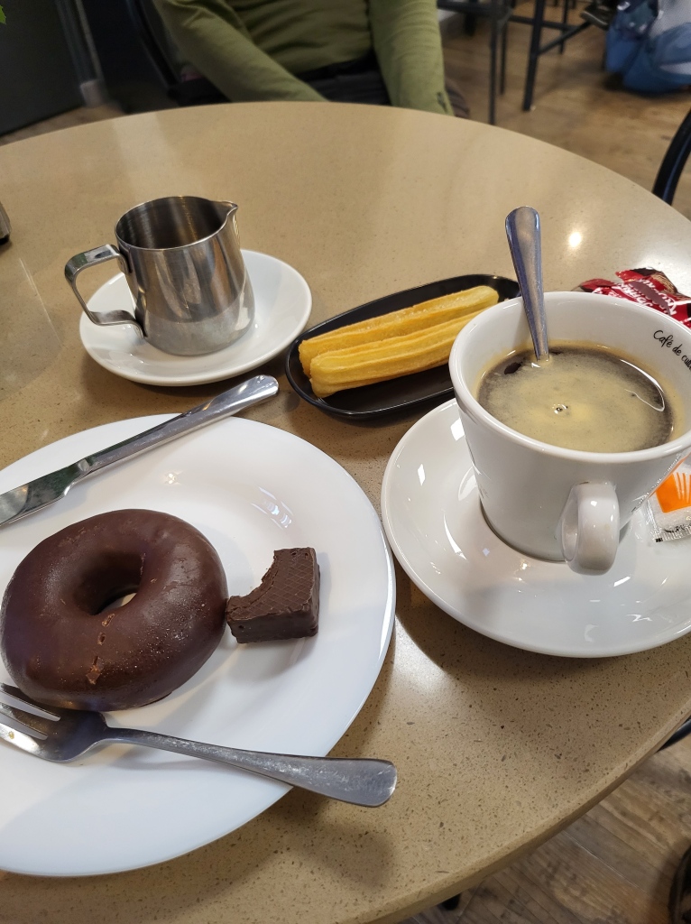 Coffee, donut, and churros on a table in Negreira, Spain.